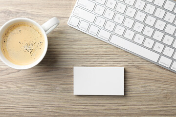 Blank business cards, coffee and keyboard on wooden table, flat lay. Mockup for design