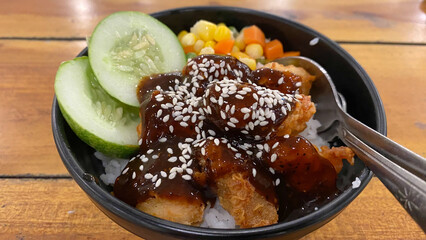 Japanese Food Style : Top view of Homemade Chicken Teriyaki grilled with rice, carrot, broccoli put on the black bowl and place on wooden table

