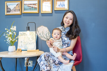 A Taiwanese woman in her 30s wearing traditional Chinese clothing sits while holding a 6-month-old baby and taking a commemorative photo on Dihua Street in Taipei City, Taiwan, in September.