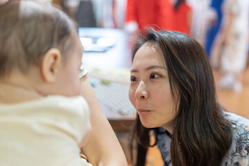 A Taiwanese woman in her 30s wearing traditional Chinese clothing is entertaining a 6-month-old baby being held by another woman on Dihua Street in Taipei City, Taiwan, in September.