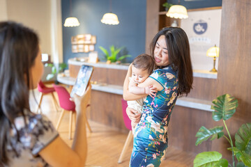 A Taiwanese woman in her 30s wearing traditional Chinese clothing is holding a 6-month-old baby while having a commemorative photo taken on Dihua Street in Taipei City, Taiwan, in September.