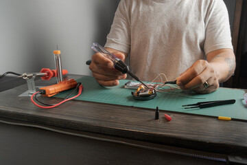 A man is working on a project, using a soldering iron to fix a circuit board