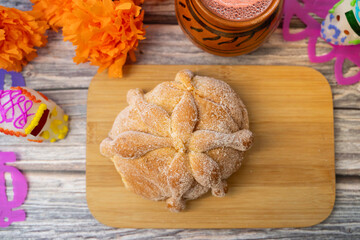 Top View of Pan de Muerto with Hot Chocolate in Clay Cup, Marigold Flowers, and Sugar Skulls