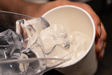 pouring ice cubes into the paper cup