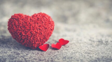 Fototapeta premium A plush red heart sits beside tiny red hearts, symbolizing affection and romance during Valentine's celebrations