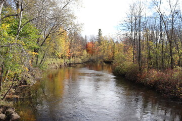 A river in autumn. Autumn background. The stream of a river and flowing water. Environment and preservation. Canada landscape and the St-Charles river in Quebec. Reflection of the water in autumn.