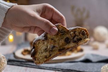 Female hand taking slice of Homemade Christmas traditional cake pie with marzipan nuts and dried fruits pastry dessert stollen. Winter holidays season atmosphere. Delicious tasty composition home