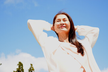 青空の下でリラックスしている笑顔のシニア女性