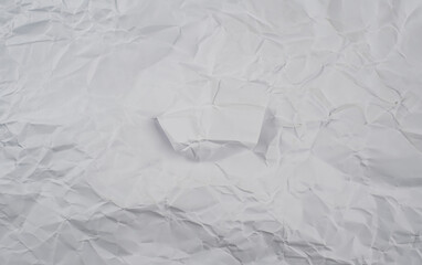 Crumpled white paper background with visible folds and creases, perfect for use in textures or design elements.