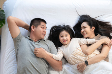 Fototapeta premium A joyful mother and daughter laughing together while lying on a bed. The playful moment showcases their strong bond and happiness in a comfortable home setting, surrounded by natural decor.