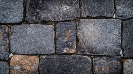 Fototapeta premium Close-up of a weathered gray stone pathway with visible grout lines and hints of green moss.