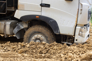 a stuck dump truck on a dirt road of a tropical island. Loose soil