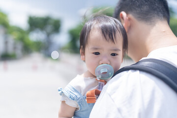 A 1 year old Taiwanese girl going out with her father, a man in his 20s, on a hot sunny day in the streets of Taichung City, Taiwan, in September.