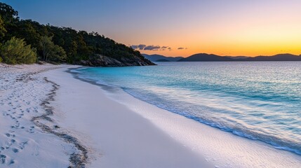 Obraz premium A peaceful beach with soft white sand and crystal-clear turquoise waters, illuminated by the warm hues of a stunning sunrise