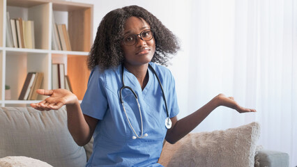 Confused doctor. Medical doubt. Unsure woman nurse in clinic uniform shrugging shoulders uncertain...