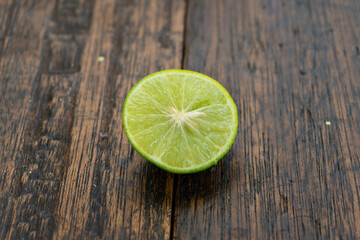 jeruk nipis or Lime green with cut in half and slices isolated on wooden background.