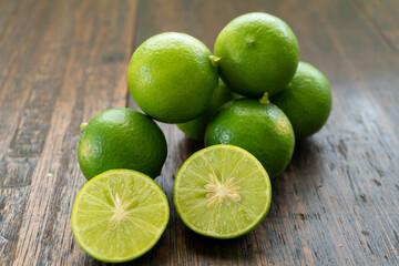 jeruk nipis or Lime green with cut in half and slices isolated on wooden background.