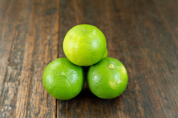 jeruk nipis or Lime green with cut in half and slices isolated on wooden background.