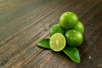jeruk nipis or Lime green with cut in half and slices isolated on wooden background.