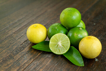 jeruk nipis or Lime green with cut in half and slices isolated on wooden background.