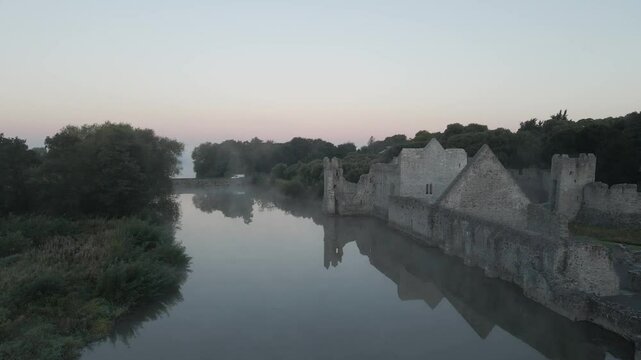 Adare Castle by a misty river at dawn with soft pastel skies in County Limerick Ireland