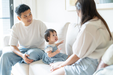 A 1 year old Taiwanese girl spending time playing happily with her parents, a man and woman in their 20s, in a room of a high rise apartment in Taichung City, Taiwan.