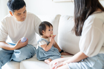 A 1 year old Taiwanese girl spending time playing happily with her parents, a man and woman in their 20s, in a room of a high rise apartment in Taichung City, Taiwan.