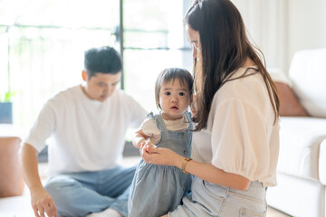 A 1 year old Taiwanese girl spending time playing happily with her parents, a man and woman in their 20s, in a room of a high rise apartment in Taichung City, Taiwan.