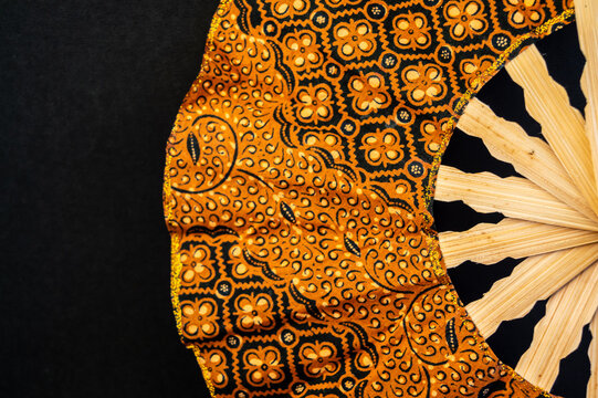 traditional hand fan, a hand fan made of wood and patterned fabric. 