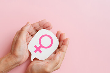 hand hold woman symbol on real white speech bubble paper cut on pink background