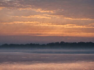 Obraz premium A tranquil dawn sky with wisps of clouds floating close to the ground, bathed in soft morning light as the day begins 