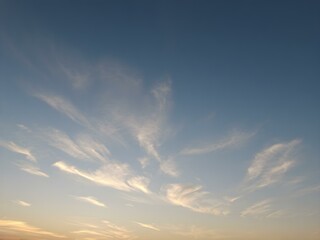 Fototapeta premium A tranquil dawn sky with wisps of clouds floating close to the ground, bathed in soft morning light as the day begins 
