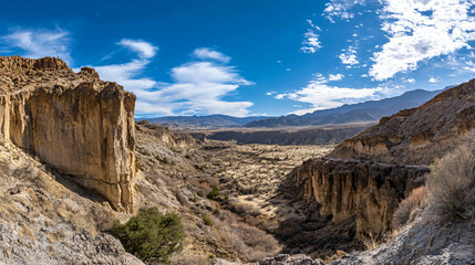 Fototapeta premium A panoramic view of a desert valley filled with dramatic cliffs.