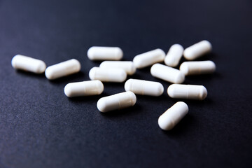 Creatine capsules on dark paper background. Soft focus. Copy space.	