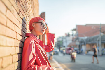 Fototapeta premium Gen z girl leather fashion with punk Asian woman tourist of local city Southeast Asia travel trendy pink hairstyle young female punk traveler walking around in town