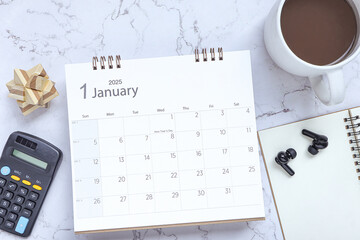 Top view of January 2025 calendar. January 2025 calendar and cup of coffee, calculator, wireless...
