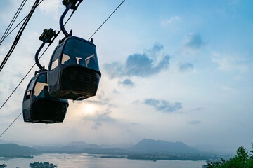 Cable cars transporting tourists over lake pichola in udaipur, india at sunset