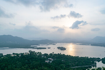 The last rays of the sun are reflecting on lake pichola, surrounded by hills and palaces in udaipur