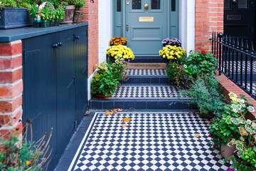 Victorian house entrance decorated with colorful flowers showing black and white checkerboard tiles