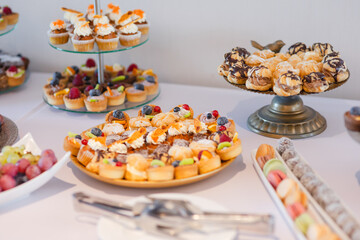 Different kinds of beautiful pastry, small colorful sweet cakes, macaron, and other dessert in the sweet buffet