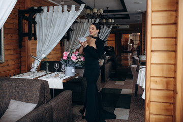 Model, a beautiful brunette woman in a black evening dress in a restaurant celebrating