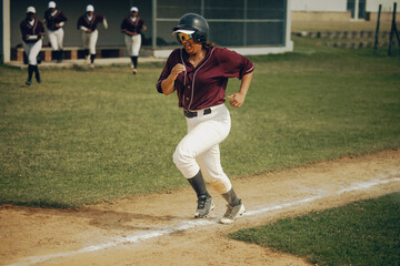 Baseball player aggressively running on base path aiming for home run during intense game