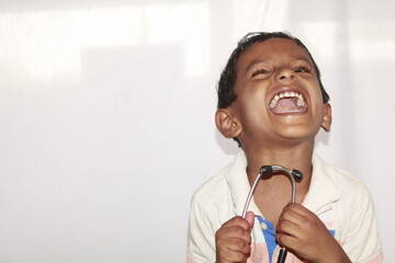 Portrait of cute littlie indian boy doctor with stethoscope and smiling isolated over white background.