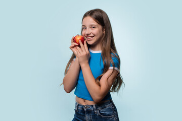Girl in blue t-shirt smiling while holding red apple