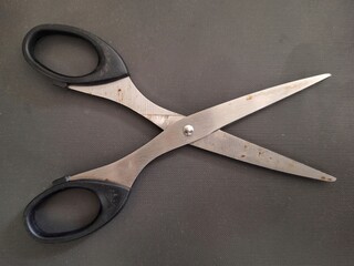 Used scissors in open position on black dark gray background