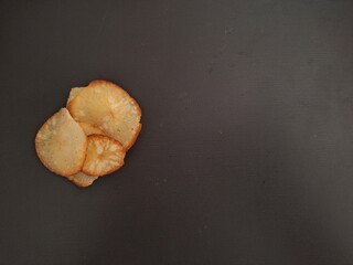 Crispy and tasty Indonesian cassava chips, with a dark gray black background, leaving copy space