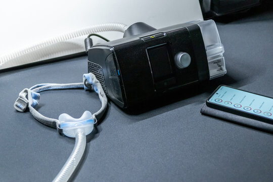 Male European with cpap machine checking therapy analysis via smartphone app or medical app for e-health check and health report via mobile device for health analysis innovative sleep apnea mask apps