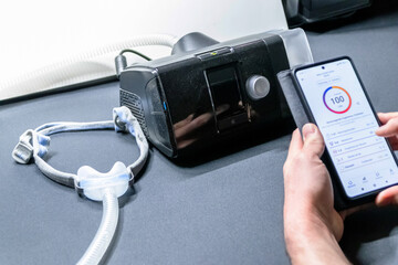 Male European with cpap machine checking therapy analysis via smartphone app or medical app for e-health check and health report via mobile device for health analysis innovative sleep apnea mask apps