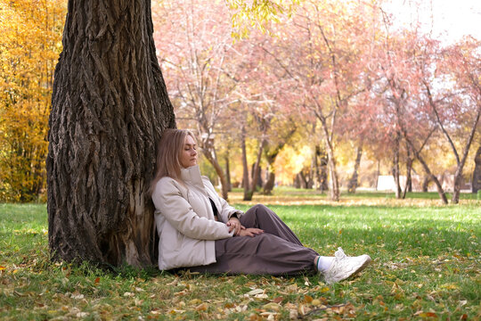 Girl gently hugs tree in forest clearing on sunny autumn day, symbolizing deep connection with nature and an exciting sense of calm in natural world. Lifestyle, Environmental Protection. - Powered by Adobe