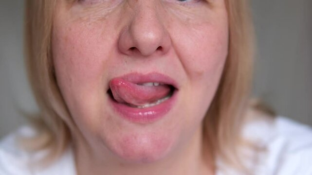 woman licking lips with tip of tongue in circle lick lips moisturizing dry lips need hygienic lipstick sexuality adult middle-aged lady female flirting close-up tongue teeth